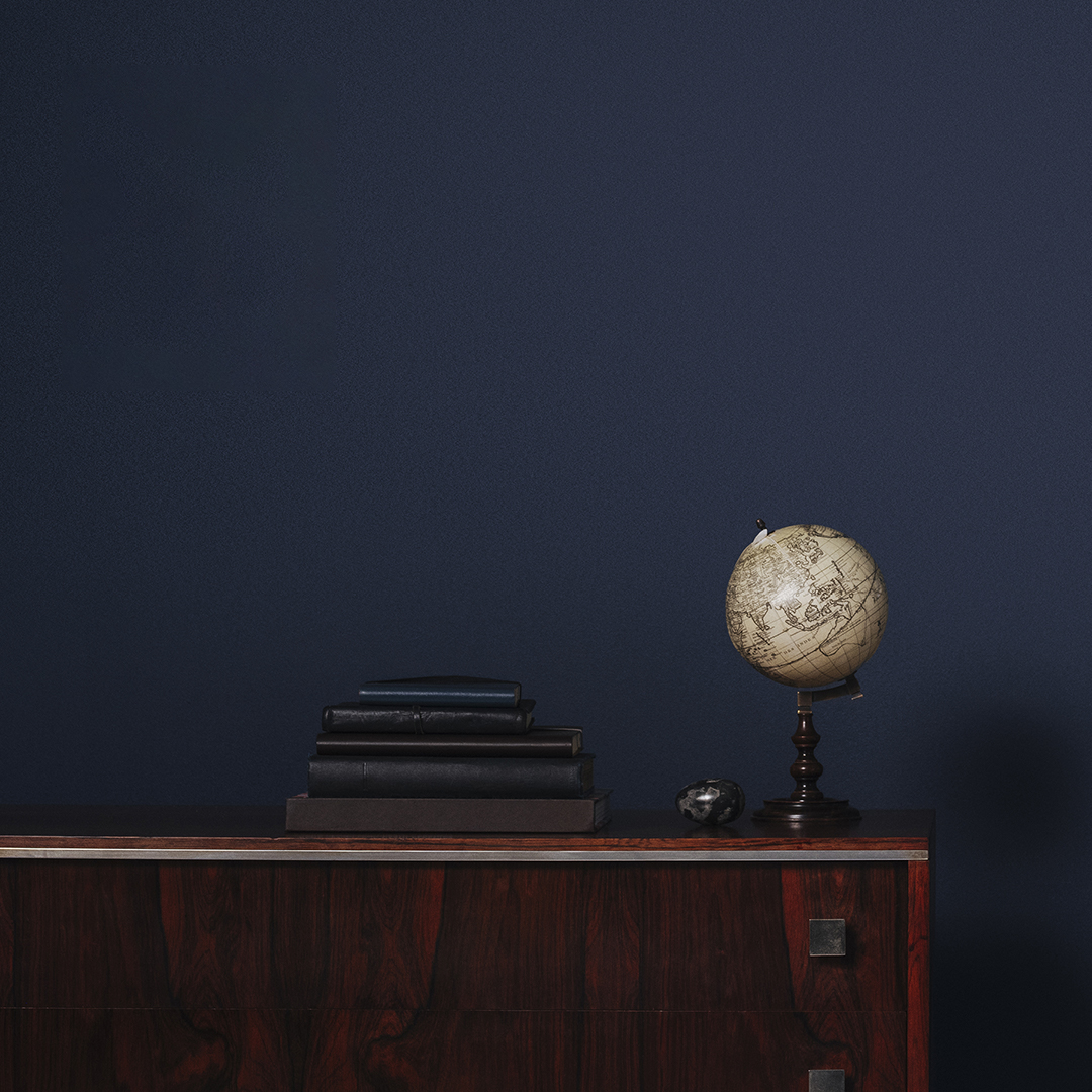 Globe on side table in front of navy blue wall