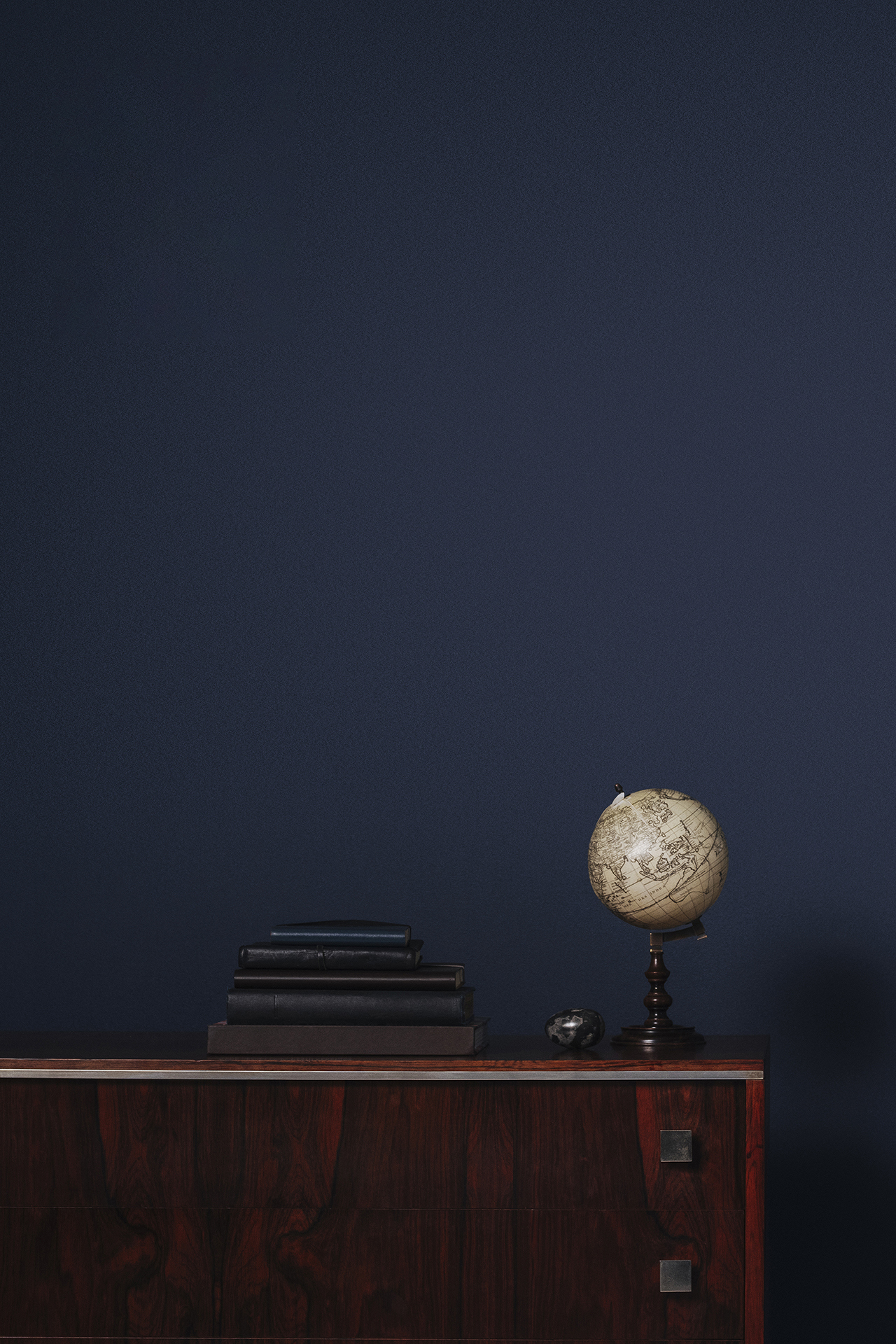 Globe on side table in front of navy blue wall